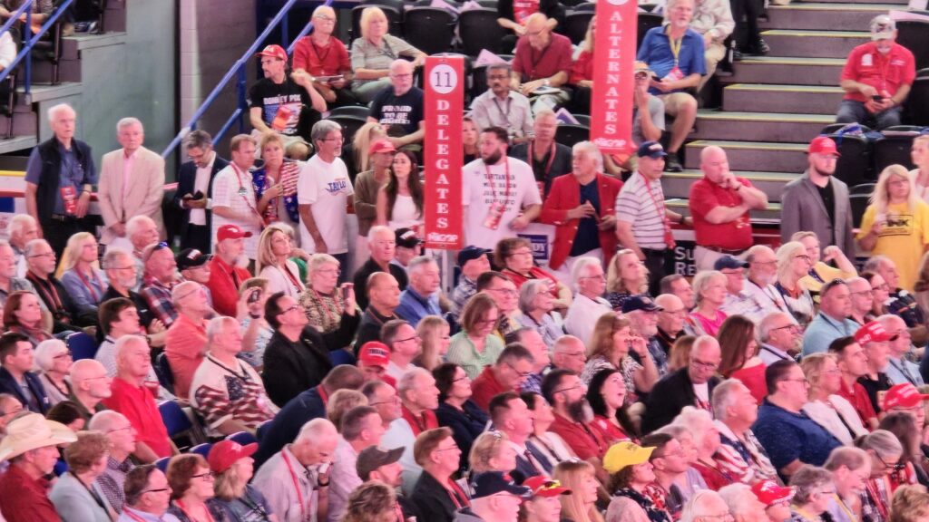 Michigan Republican convention delegates seated beneath district signs