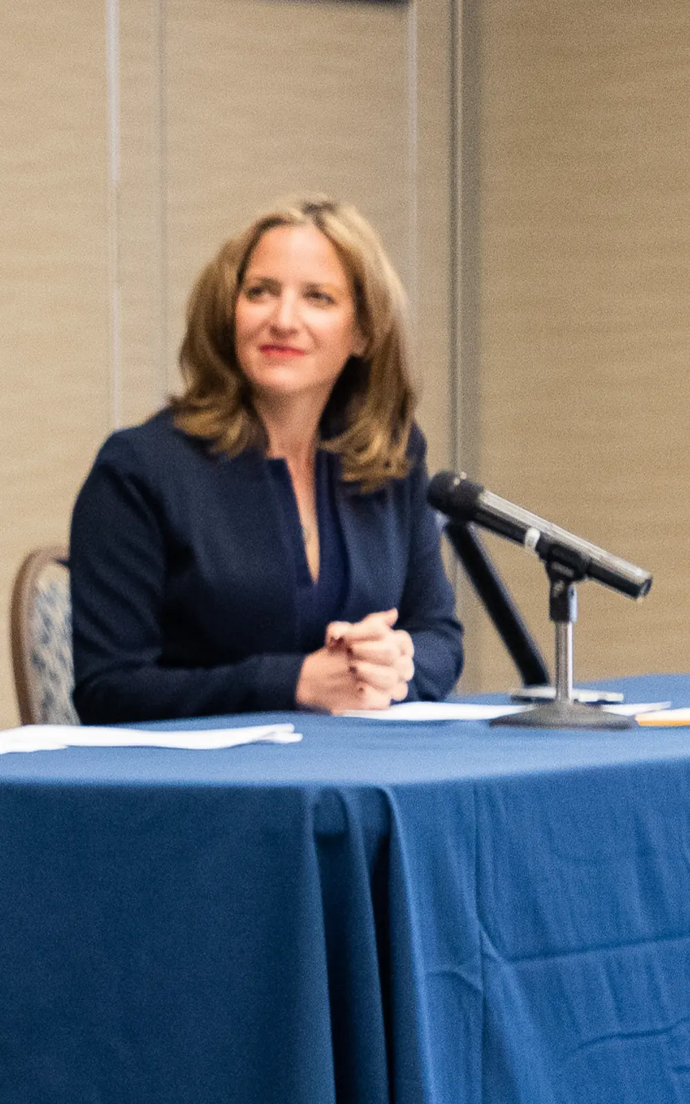 Jocelyn Benson seated at a panel discussion table with a microphone