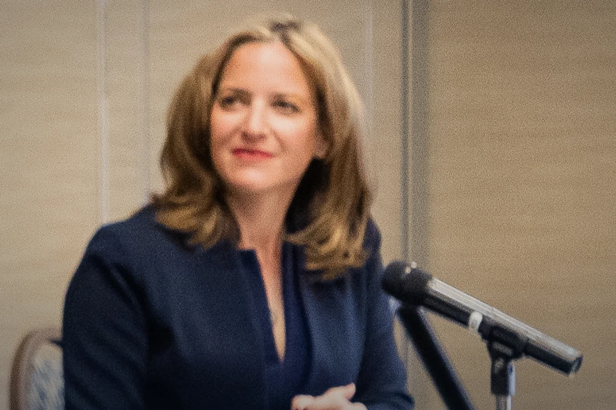 Jocelyn Benson seated at a panel discussion table with a microphone