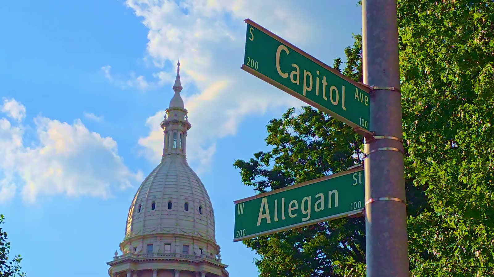 The Capitol dome behind the Capitol Avenue and West Allegan Street signs in Lansing.